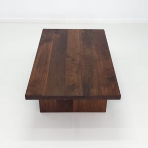 Solid walnut LILY coffee table with a thick slab top and panel legs, showcasing rich wood grain.