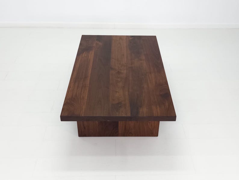 Solid walnut LILY coffee table with a thick slab top and panel legs, showcasing rich wood grain.
