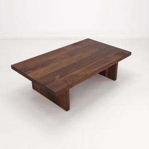 Solid walnut LILY coffee table with a thick slab top and panel legs, showcasing rich wood grain.