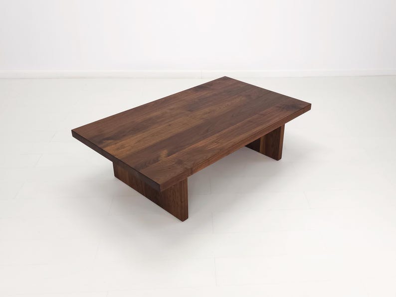 Solid walnut LILY coffee table with a thick slab top and panel legs, showcasing rich wood grain.