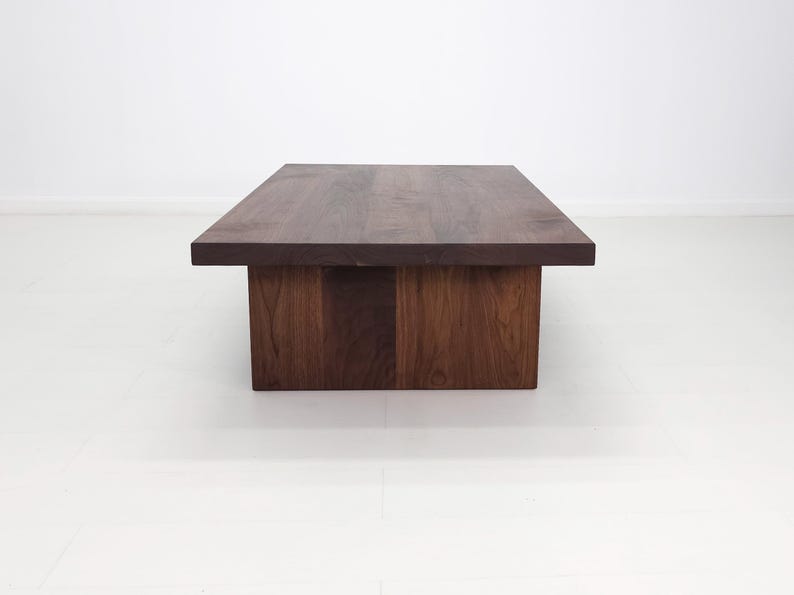Solid walnut LILY coffee table with a thick slab top and panel legs, showcasing rich wood grain.
