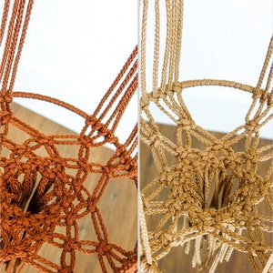May include: Two macrame plant hangers, one in brown and one in beige, with fringe details. The hangers are made of cotton cord and have a knotted design.