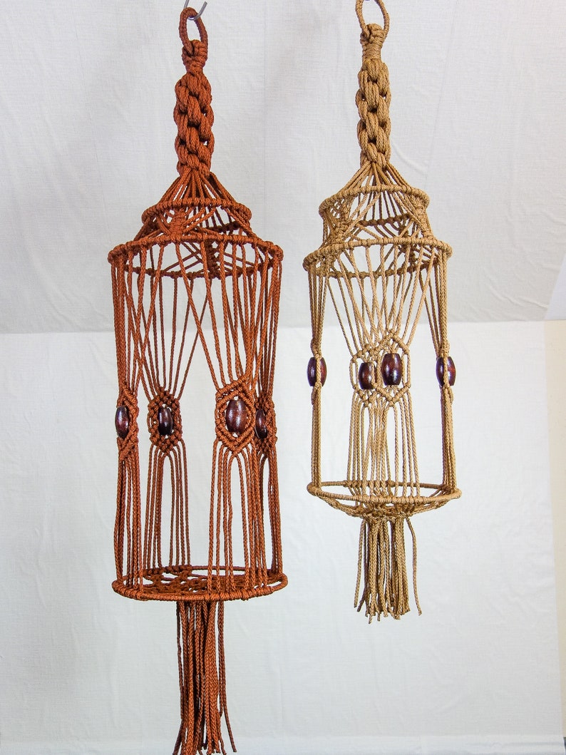 May include: Two macrame plant hangers with wooden beads. The hanger on the left is brown and the hanger on the right is beige.