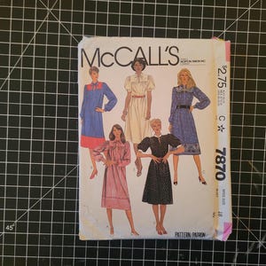 May include: McCall's sewing pattern number 7870 for a dress. The pattern shows four different styles of dresses, all with long sleeves and a variety of necklines. The pattern is priced at $2.75.