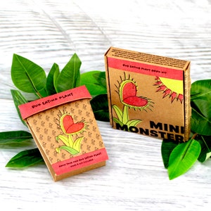 May include: A brown cardboard box with a red heart-shaped bug-eating plant illustration. The box says "Mini Monster" and "Bug Eating Plant Grow Kit".