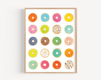 May include: A framed print featuring a grid of colorful watercolor donuts. Each donut has a different color frosting and sprinkles, including pink, blue, green, and orange. The donuts are arranged on a white background.