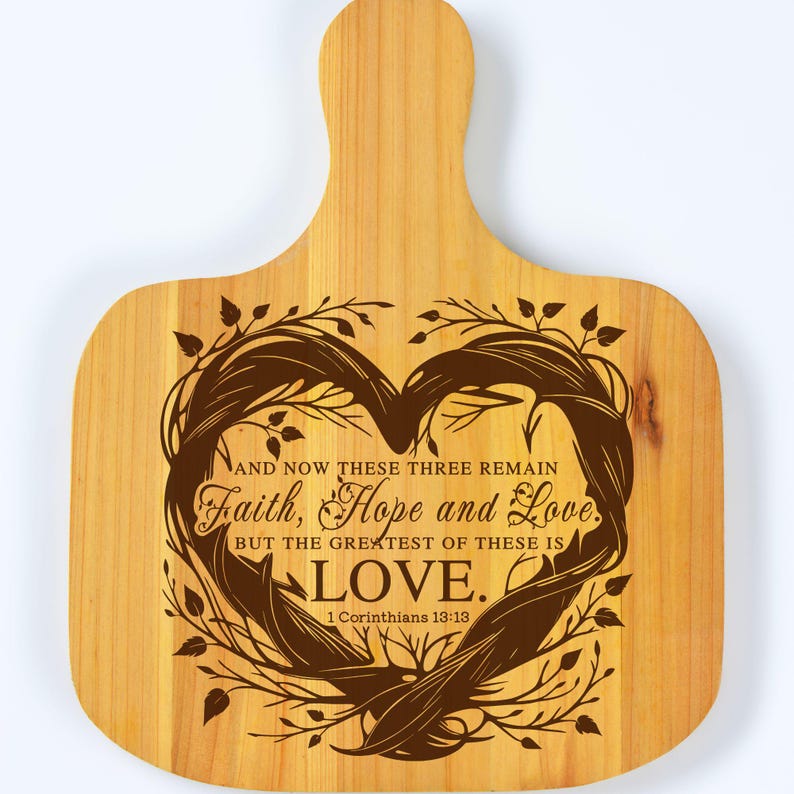 Puede incluir: Una tabla de cortar de madera con un dise&ntilde;o en forma de coraz&oacute;n y el texto "AND NOW THESE THREE REMAIN Faith, Hope and Love. BUT THE GREATEST OF THESE IS LOVE. 1 Corinthians 13:13".