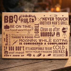Op de afbeelding: Houten snijplank met gegraveerde BBQ-regels en illustraties. Het bord bevat zinnen als "Raak nooit de grill van een andere man aan" en "Ruim na jezelf op".