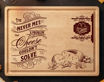 May include: A rectangular wooden cheese board with a recessed edge. The board features engraved text that reads "I've never met a problem that cheese couldn't solve." A cheese shop logo and cheese illustrations are also engraved.