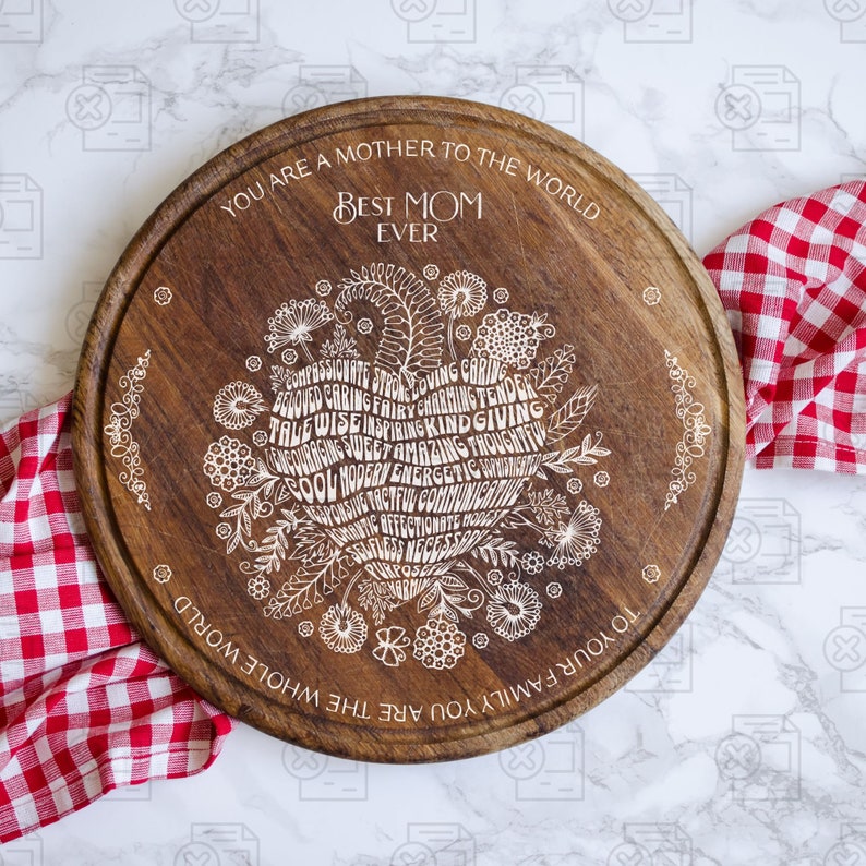 May include: A round wooden serving board with a white design of a heart made of words. The words include "Best Mom Ever" and "You are a mother to the world". The board is perfect for serving cheese, crackers, or other snacks.