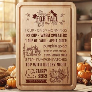 May include: A rectangular light-colored wooden cutting board featuring a laser-engraved design titled Recipe FOR FALL. The text lists ingredients like crisp mornings, warm sweaters, apple cider, pumpkin spice, hot cocoa, and football games.