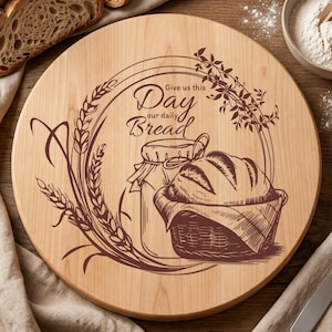May include: A circular wooden chopping board featuring a bread-themed illustration. The design includes a loaf of bread in a basket, a jar, wheat stalks, and the text "Give us this day our daily bread".