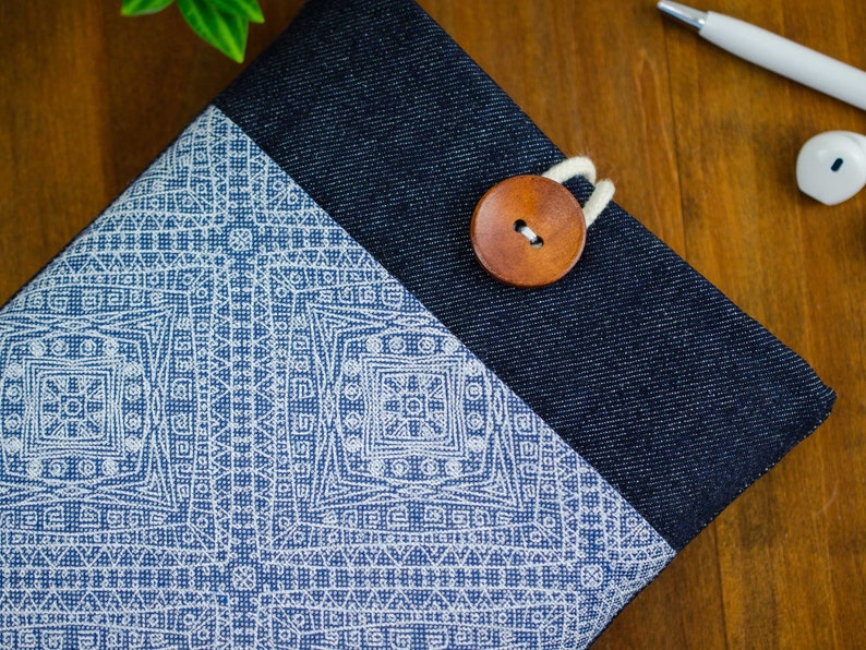 May include: A blue denim and white fabric pouch with a wooden button closure. The pouch has a geometric pattern on the front.
