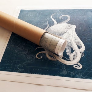 May include: A rolled up nautical map with a vintage illustration of an octopus on a blue background. The map is labeled "Ocean Atlantique du Nord" and "Amerique Meridionale".
