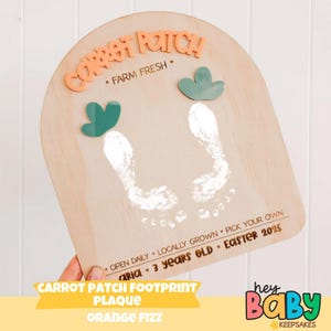 May include: Wooden Carrot Patch footprint plaque with orange text and green accents. Features footprints, the text "Carrot Patch", "Farm Fresh", and "Easter 2025". Includes the text "Aria 3 years old".