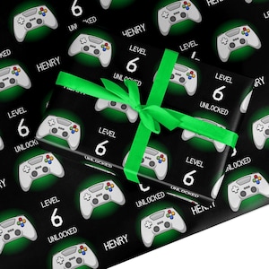 May include: Black and green wrapping paper with a repeating pattern of video game controllers and the text "Level 6 Unlocked" and "Henry".