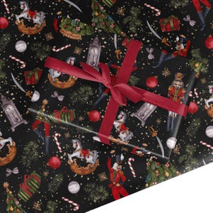 May include: Black and white wrapping paper with a repeating pattern of nutcrackers, rocking horses, candy canes, Christmas trees, and baubles. The paper is wrapped around a gift box with a red ribbon.