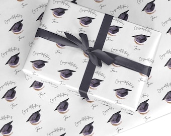 Peut inclure: Papier d'emballage blanc avec un motif répété de chapeaux de graduation noirs et le texte "Congratulations Jane".