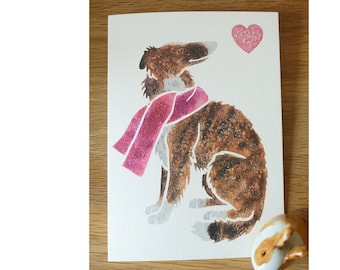 May include: A watercolor illustration of a brown and white dog wearing a pink scarf. A pink heart is in the upper right corner of the card.