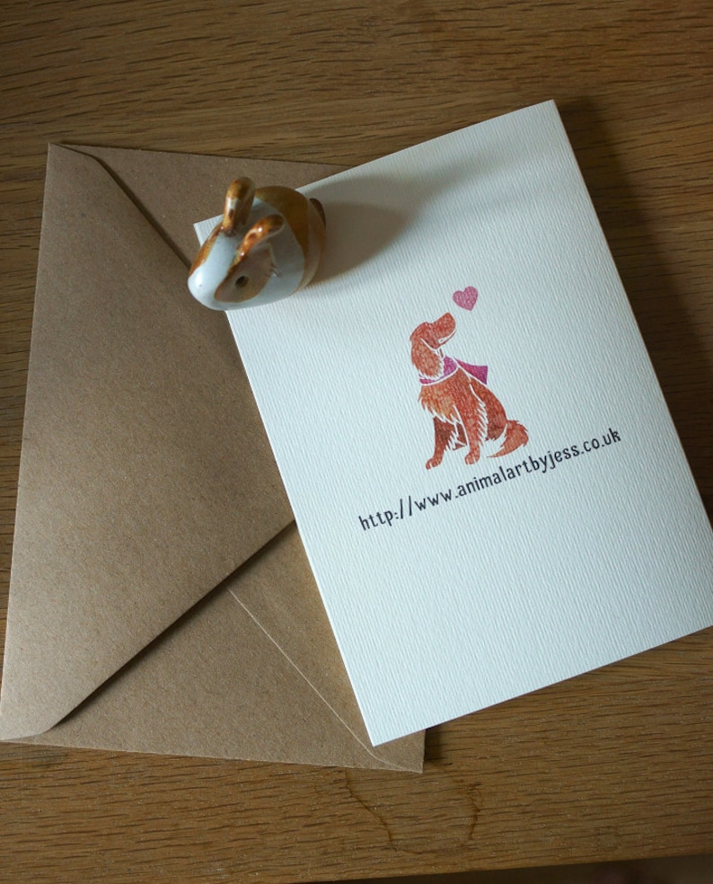 May include: A white card with a brown dog illustration and a pink heart. The text on the card reads "http://www.animalartbyjess.co.uk".