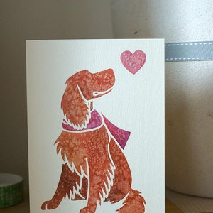 May include: A watercolor illustration of a brown dog with a pink scarf looking up at a pink heart. The dog is sitting on a white card.
