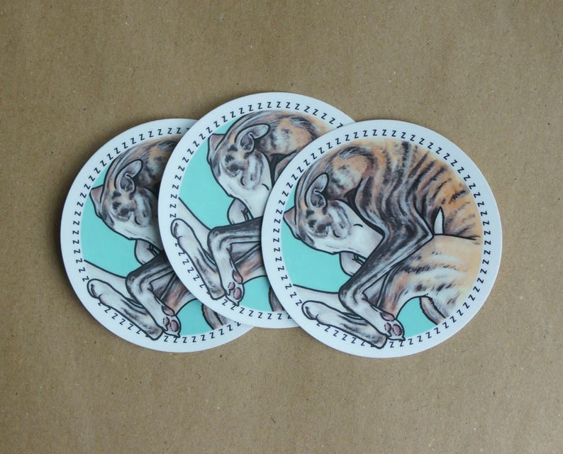 Three sleeping Whippet dog stickers against a brown paper background