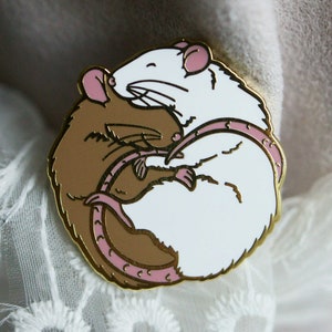 A circular enamel pin showing two sleeping rats embracing. The left hand rat is brown/agouti and the right hand one is white. The plating (outline) colour is gold.