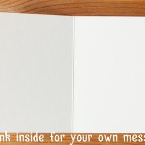May include: Blank white card with a textured surface. The card is folded in half and is ready for a message.