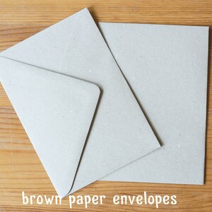 May include: Two brown paper envelopes on a wooden surface. The envelopes are blank and have a rough texture.