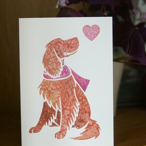 May include: A watercolor illustration of a dog with a pink scarf looking up at a pink heart. The dog is sitting and has a brown and pink color scheme.