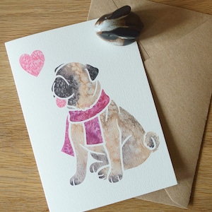 May include: A watercolor illustration of a pug wearing a pink scarf with a pink heart in the corner. The card is white with a textured surface.