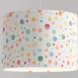 Può includere: Paralume bianco con un motivo a pois colorati. I pois sono di diverse tonalità di blu, verde, giallo, arancione e rosa.