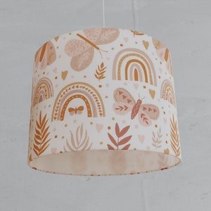 May include: A white lampshade with a pattern of rainbows, butterflies, and leaves in shades of pink, orange, and brown.