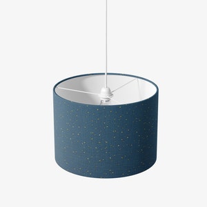 May include: A blue and gold pendant light with a white cord. The shade is a cylindrical shape with a blue fabric exterior and gold flecks.