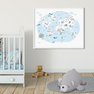 May include: A framed world map with a blue background and illustrated animals from different continents. The map is in a white frame and is hanging on a white wall. There is a white crib with a blue and white patterned sheet and a gray and white striped pillow in the foreground.