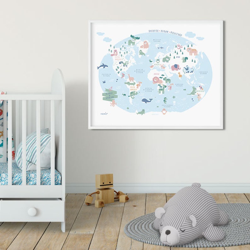 May include: A framed world map with a blue background and illustrated animals from different continents. The map is in a white frame and is hanging on a white wall. There is a white crib with a blue and white patterned sheet and a gray and white striped pillow in the foreground.
