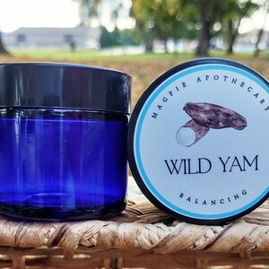 Puede incluir: Un tarro de vidrio azul con tapa negra y una etiqueta blanca que dice "MAGPIE APOTHECARY WILD YAM BALANCING". La etiqueta tambi&eacute;n presenta un dibujo de un &ntilde;ame silvestre.