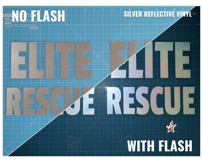 May include: A comparison of silver reflective vinyl with and without flash. The words "ELITE RESCUE" are printed in silver reflective vinyl on a blue background. The left side of the image shows the vinyl without flash, and the right side shows the vinyl with flash. The vinyl is much brighter and more reflective when viewed with flash.