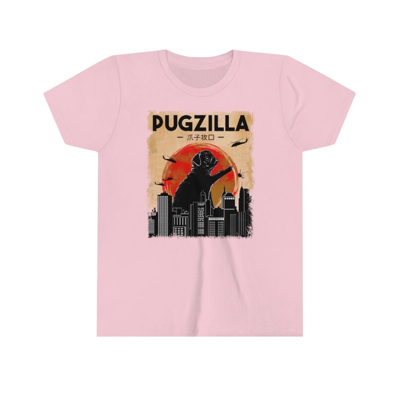 May include: A pink t-shirt with a black graphic of a pug standing on a city skyline. The graphic says "Pugzilla - パグジラ -" in black text.