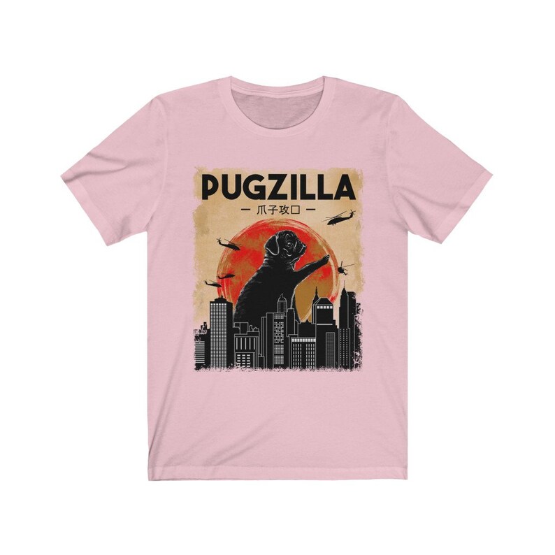 May include: A pink t-shirt with a black graphic of a pug standing on a city skyline. The graphic says "Pugzilla -  パグジラ - "