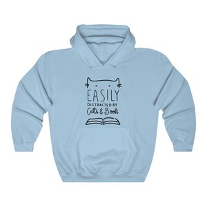 May include: Light blue hooded sweatshirt with a black graphic that says "Easily Distracted by Cats & Books" with a cat head and an open book.
