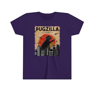 May include: Purple youth t-shirt with a vintage-style graphic of a pug standing on a city skyline with the text "Pugzilla - パグジラ -" above it.