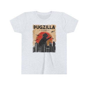 May include: A light grey t-shirt with a graphic print of a black pug standing on a city skyline. The text "PUGZILLA -  パグジラ -" is printed above the pug.