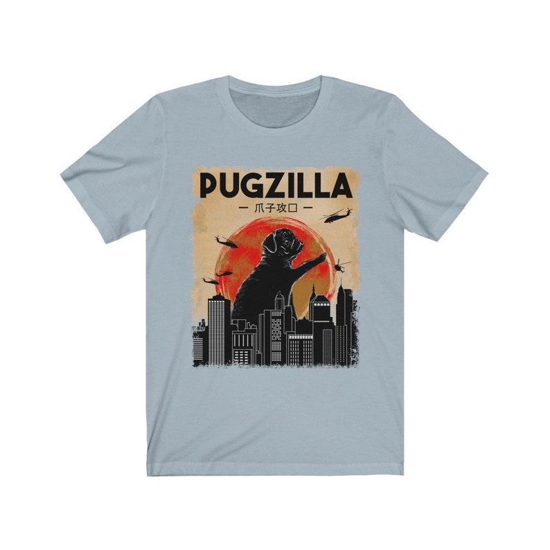 May include: A light blue t-shirt with a graphic of a black pug standing on a city skyline with the text "Pugzilla -  パグジラ -" in black.