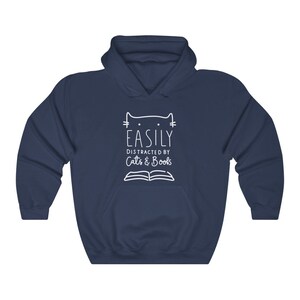 May include: Navy blue hooded sweatshirt with a white graphic design that says "Easily Distracted by Cats & Books" with a cat head and an open book.