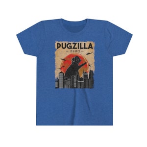 May include: A blue t-shirt with a vintage-style graphic of a pug standing on a city skyline. The graphic says "Pugzilla -  パグジラ - "