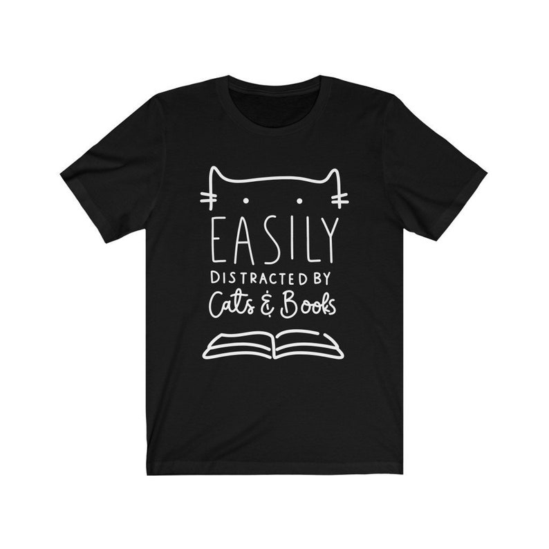 May include: Black t-shirt with a white outline of a cat and the text "EASILY DISTRACTED BY Cats & Books".