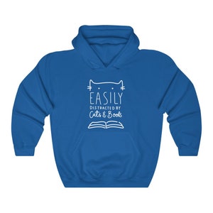 May include: A royal blue hooded sweatshirt with a white graphic design that says "Easily Distracted by Cats & Books" with a cat head and an open book.