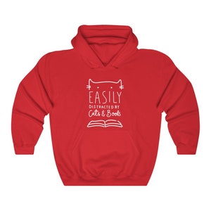May include: Red hooded sweatshirt with a white graphic design that says "Easily Distracted by Cats & Books" with a cat head and an open book.