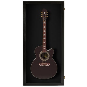 May include: A dark brown acoustic guitar with gold tuning pegs and a black pickguard is displayed in a black wood frame with a black velvet background.